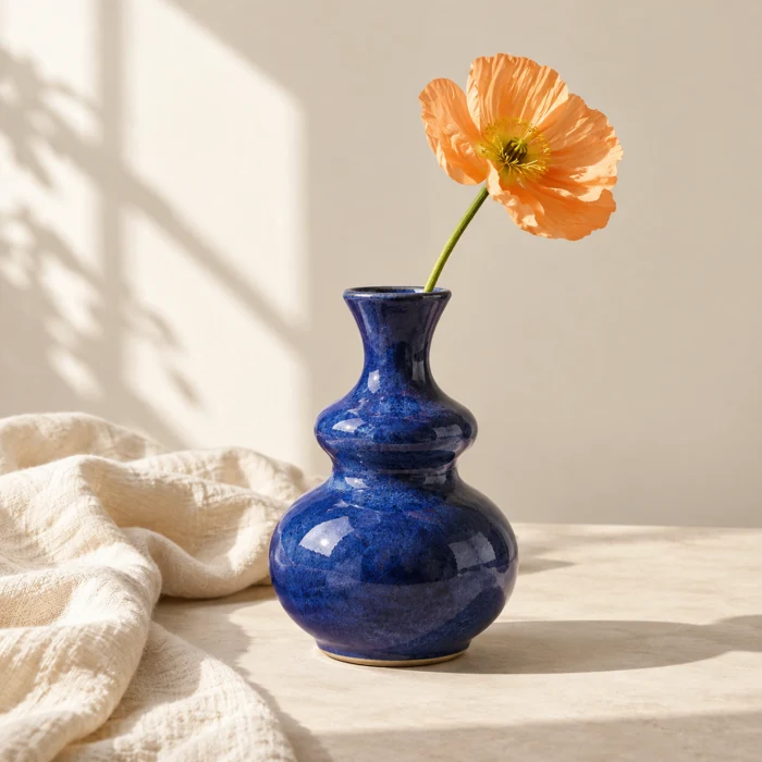 A blue ceramic vase with a pale orange flower
